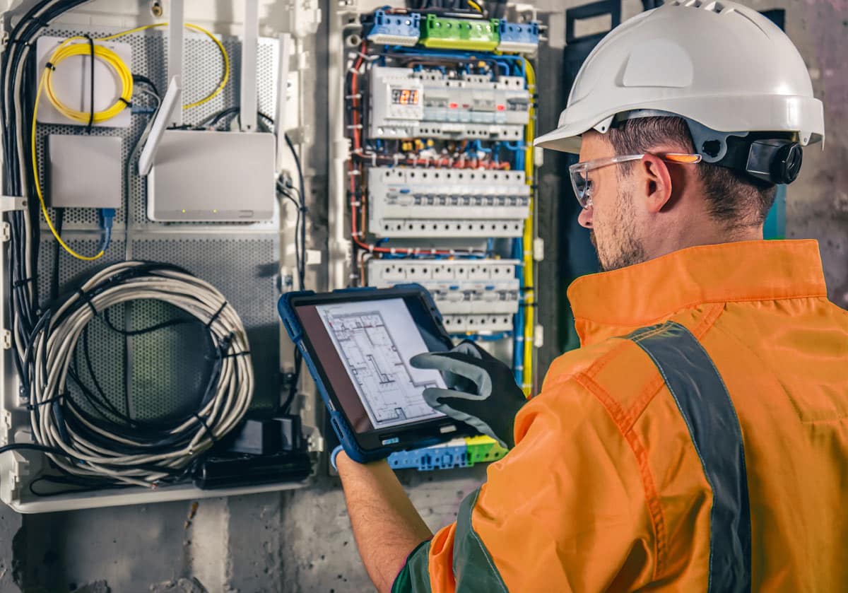 Commercial electrician performing routine maintenance on electrical panel in London office building