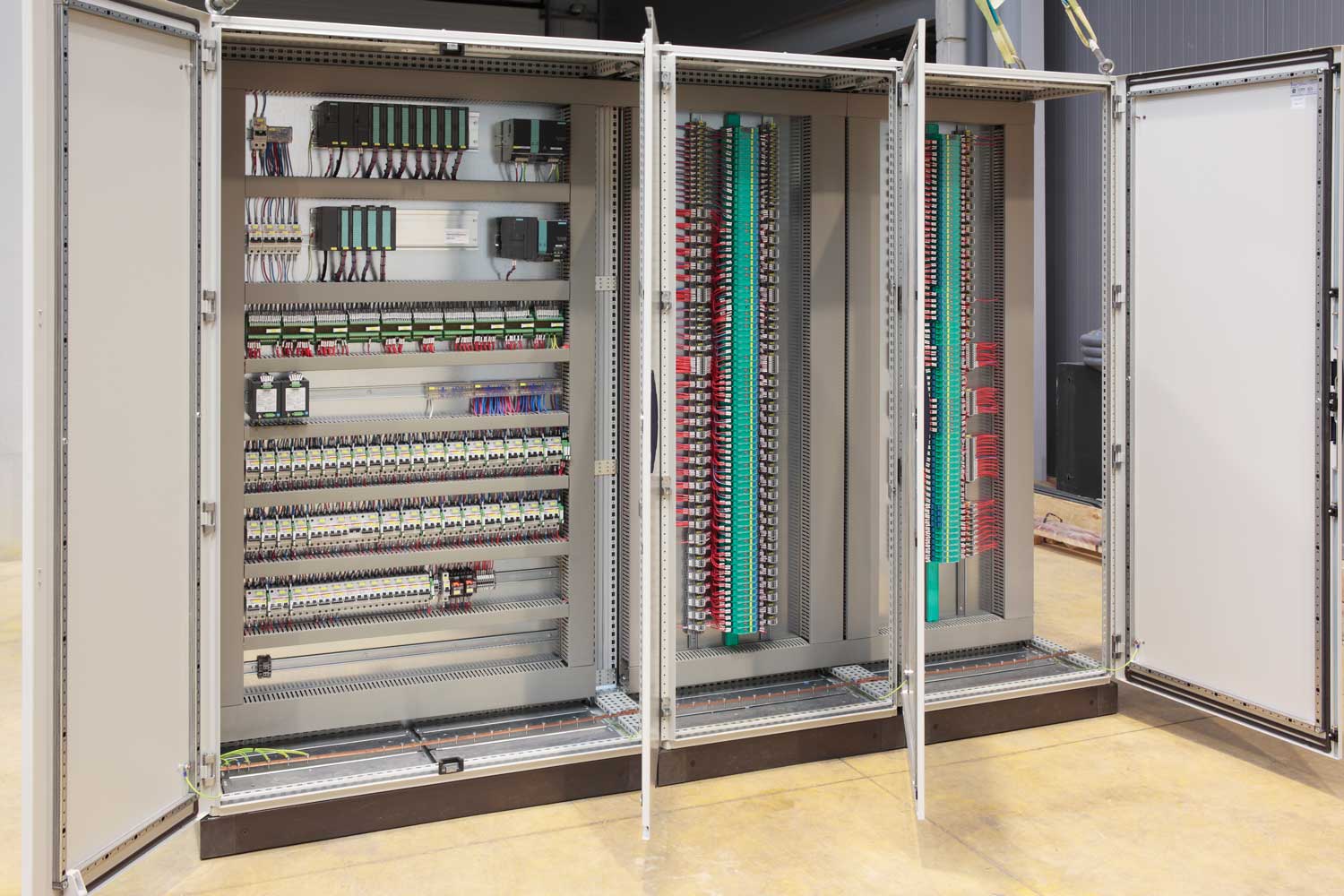 Industrial electrician wiring control panel with relays and contactors in a London factory