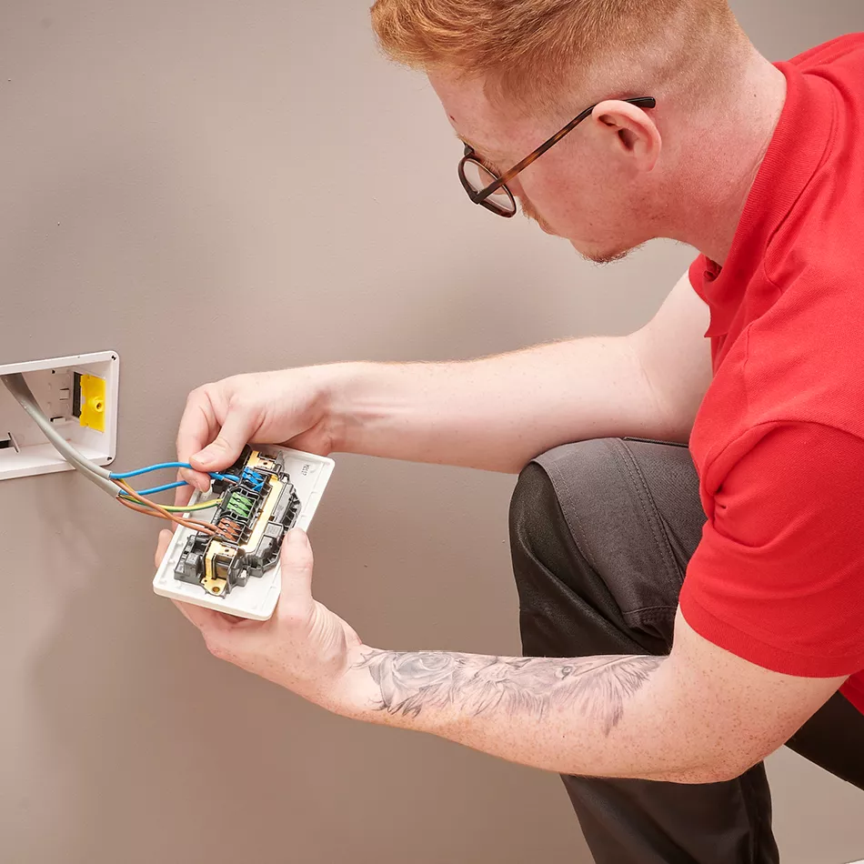 Electrician installing modern USB wall socket in a London apartment